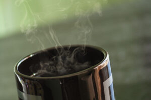 Black cup of coffe with steam rising from it.
